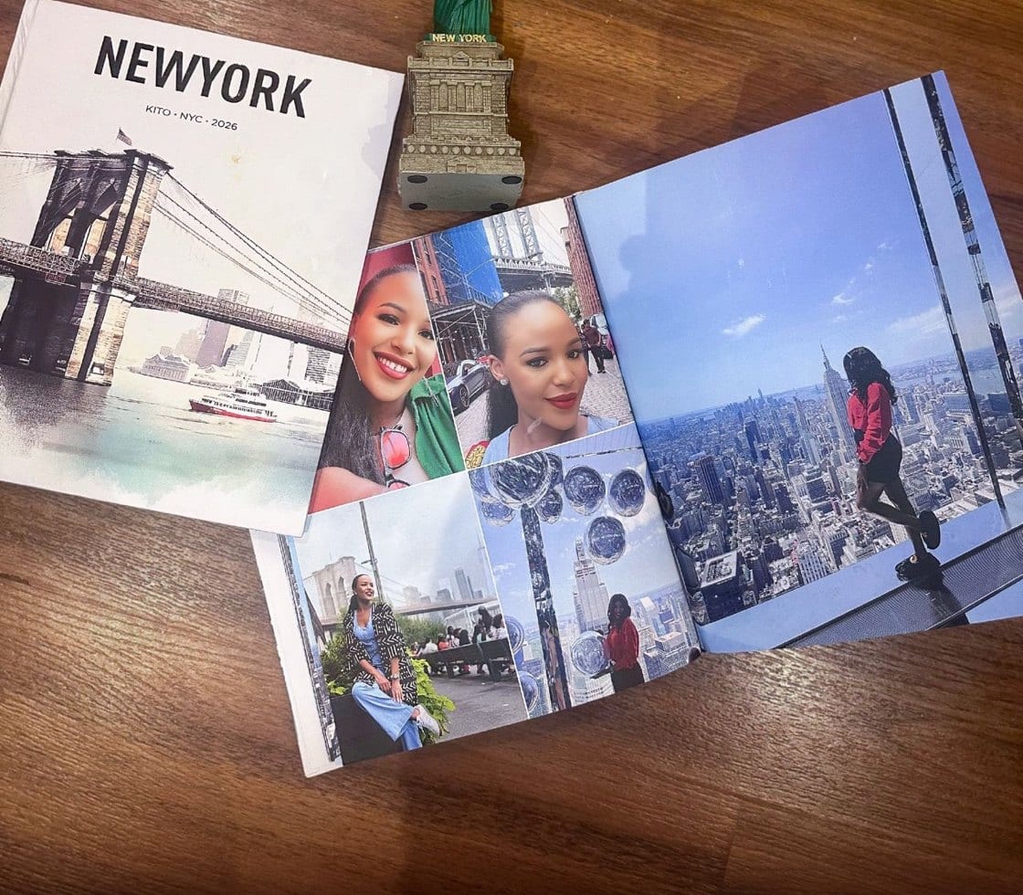 A Kito New York travel book lying open on a wood table beside its cover, showing a spread of city photographs.