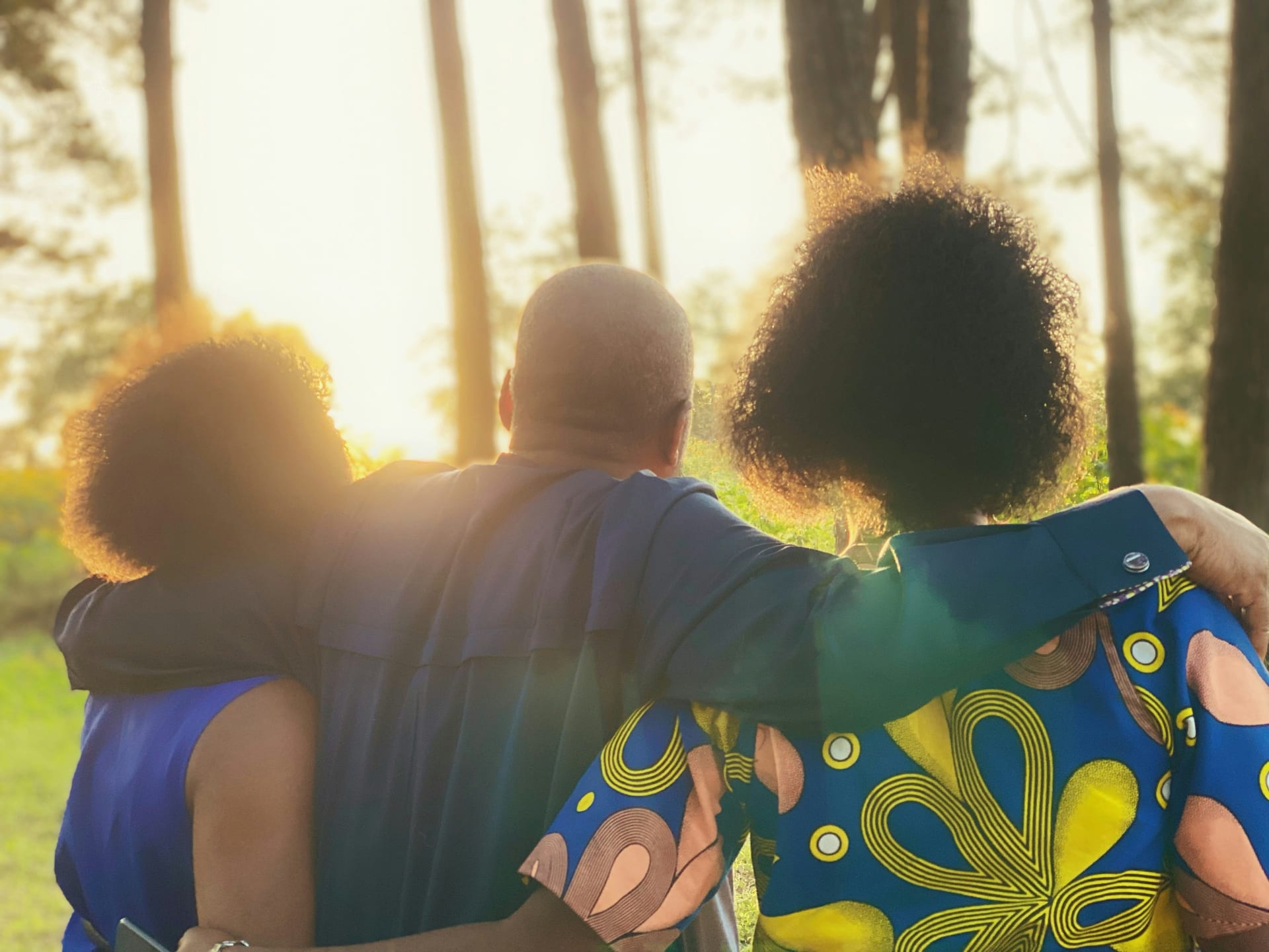A family walking away hand in hand through a bright green forest.