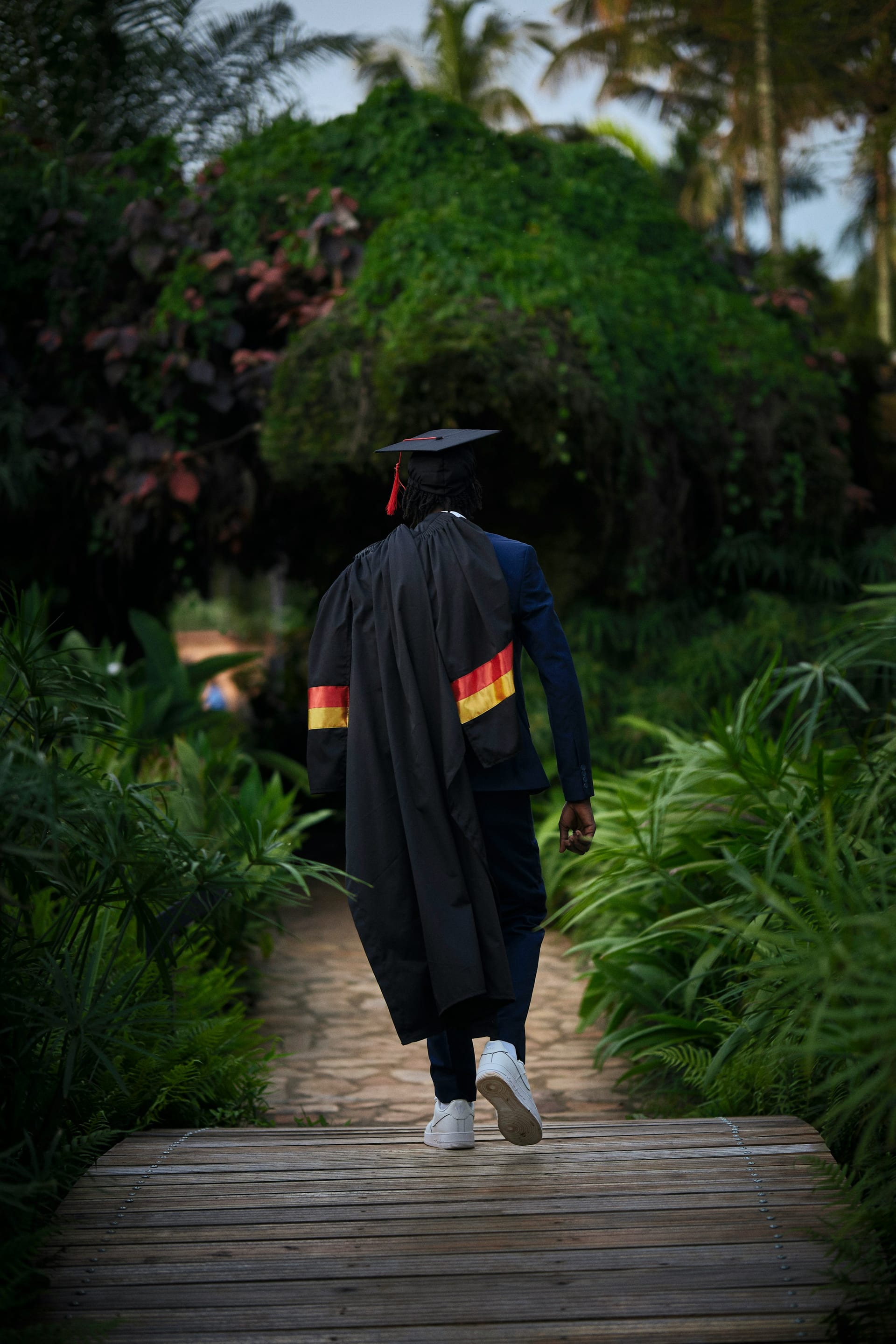 Two graduates in green gowns embracing beside a lake after the ceremony.