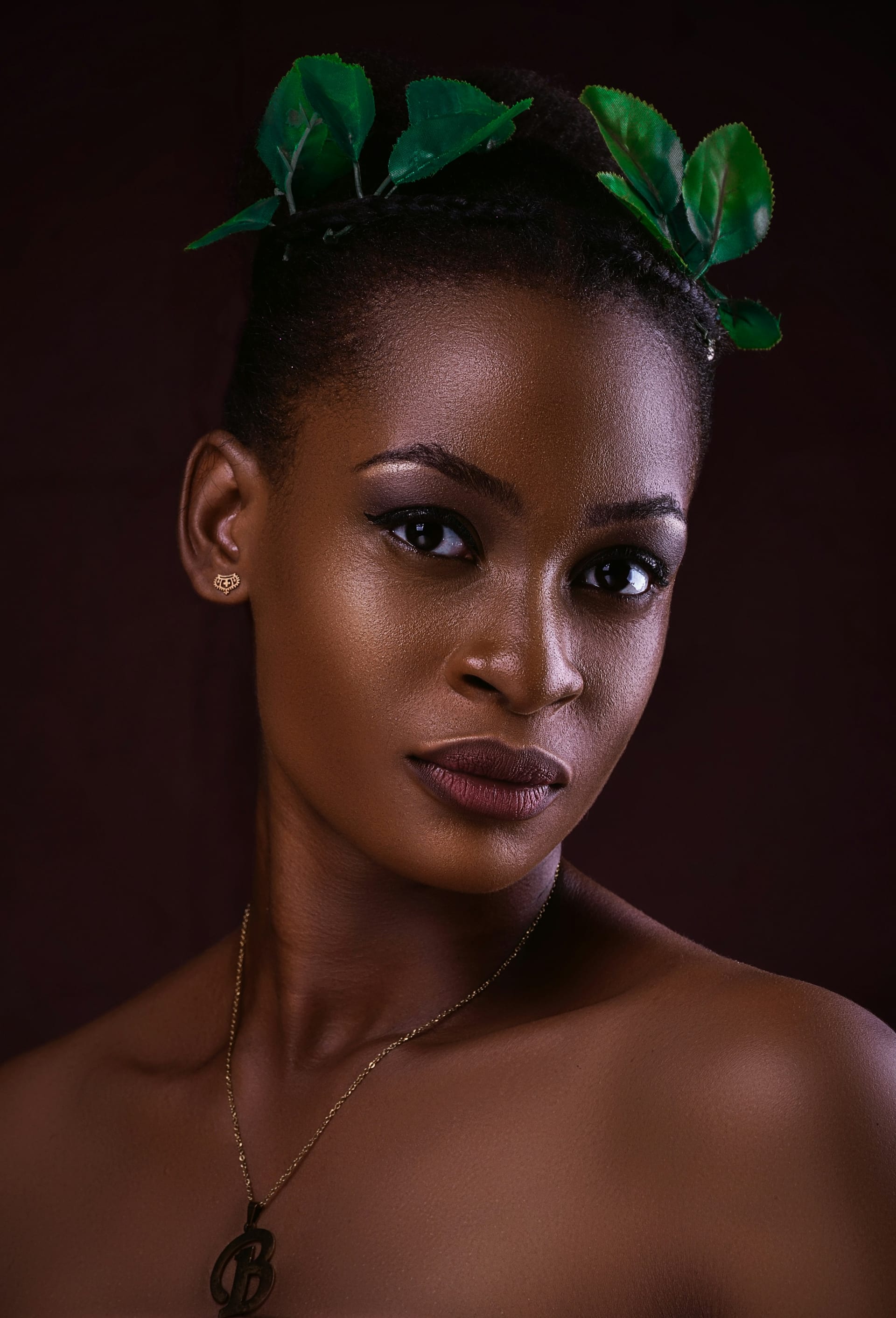 Portrait of Alice Wanjiru, looking to camera against a deep red background.