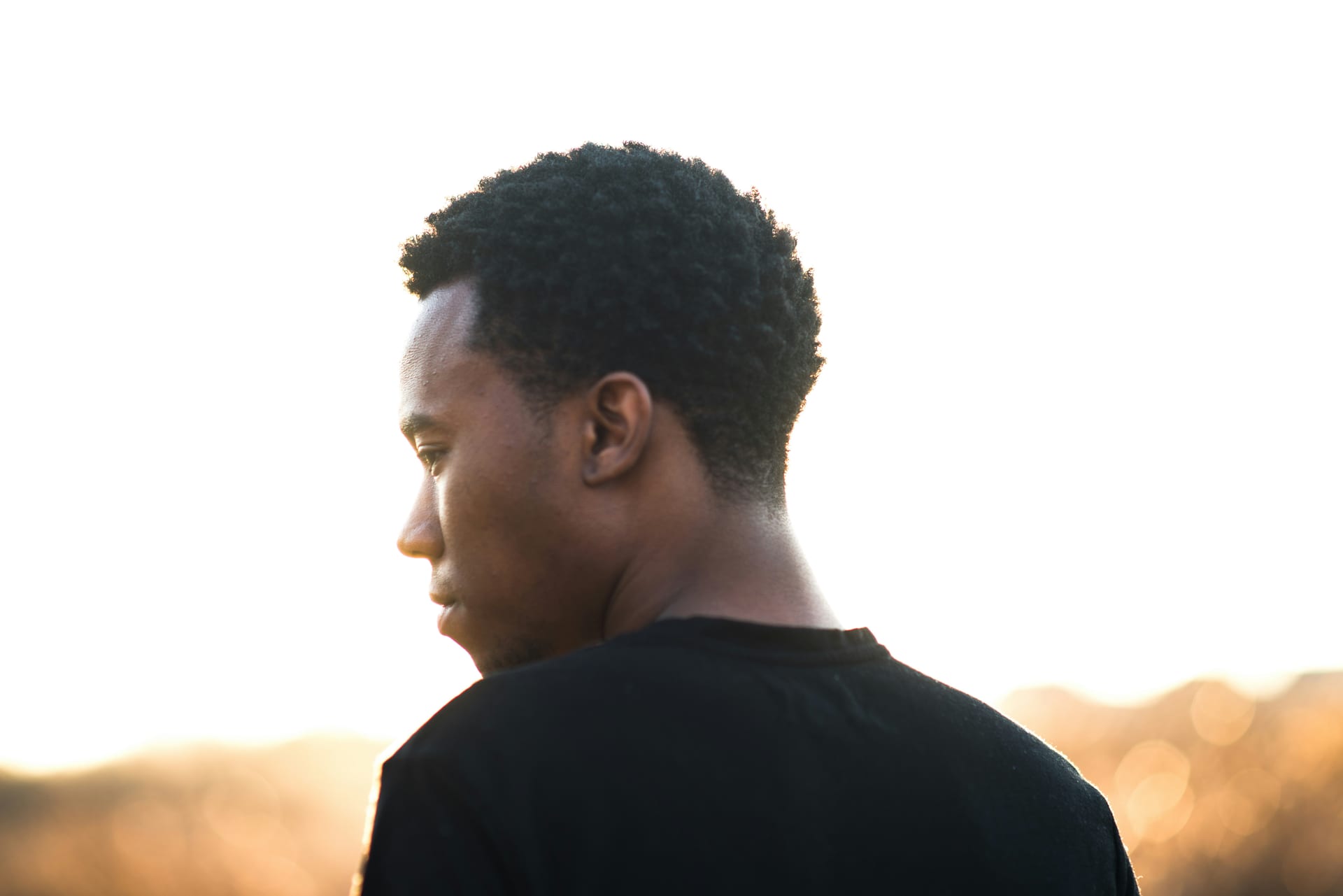 Portrait of David Osei outdoors, city light behind him.